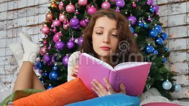 年轻的黑发正在阅读一本关于优雅圣诞树背景的书。 非常规色，创意